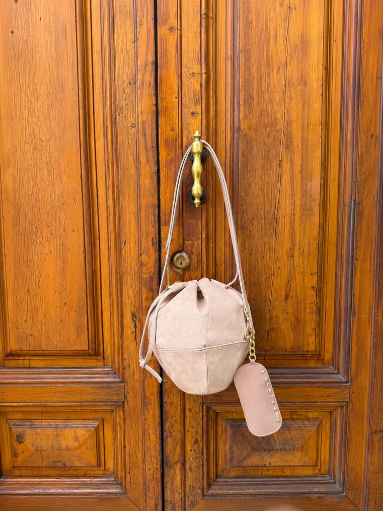 Sunday sphere bag hanging from a brass handle on a Florentine door